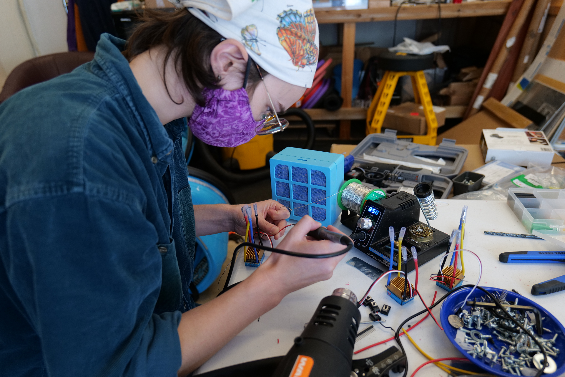 A volunteer carefully soldering wiring inside a custom blue Wayfinder™ build.